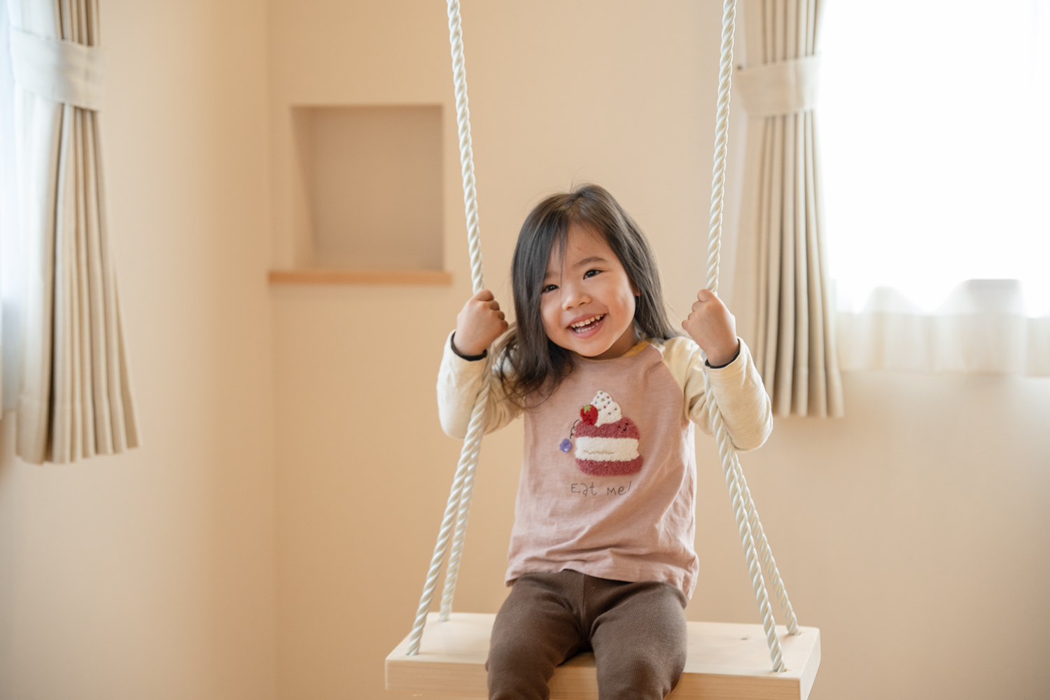 室内ブランコで楽しそうに笑う子供／遊び心を取り入れた子育て住宅