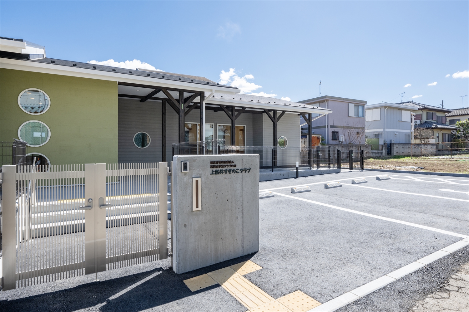 所沢市上新井小学校学童クラブの正面入口。門柱とゲートが設置された新築建物。