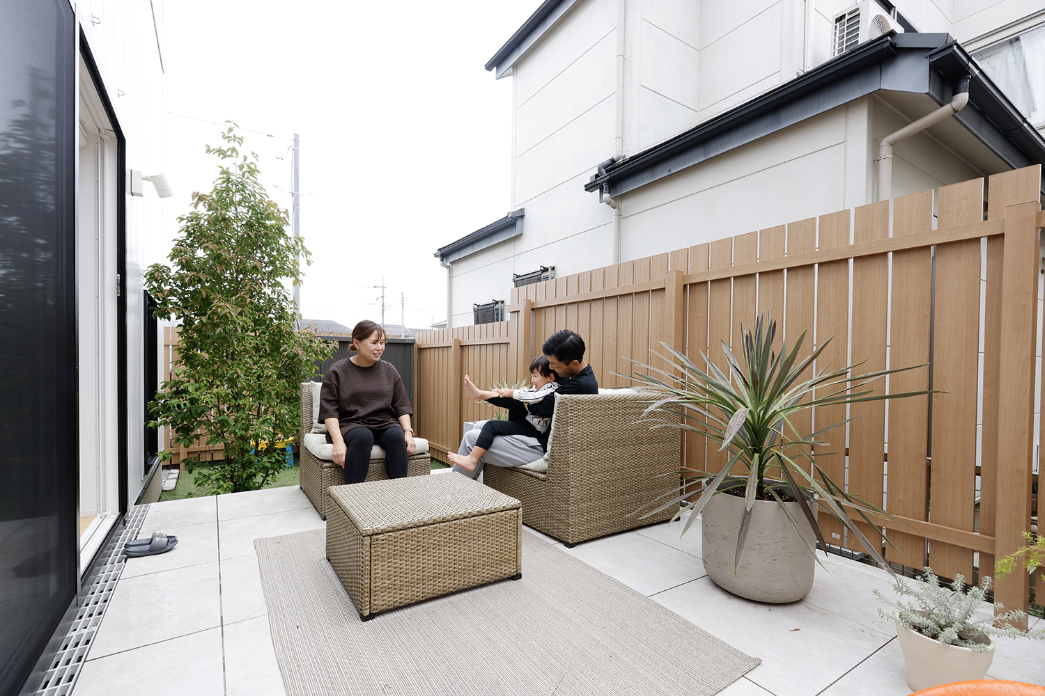 LDKとフラットにつながるタイルデッキのアウトドアリビングと目隠しフェンス