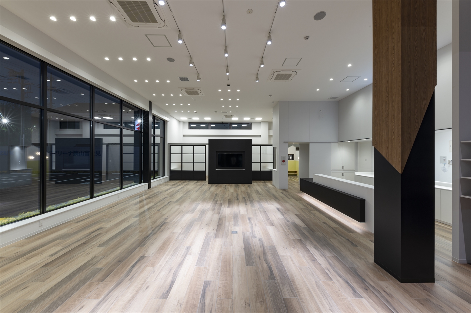 スズキトラスト本社1階ショールーム、受付カウンターと商談ブースが並ぶ自動車販売空間