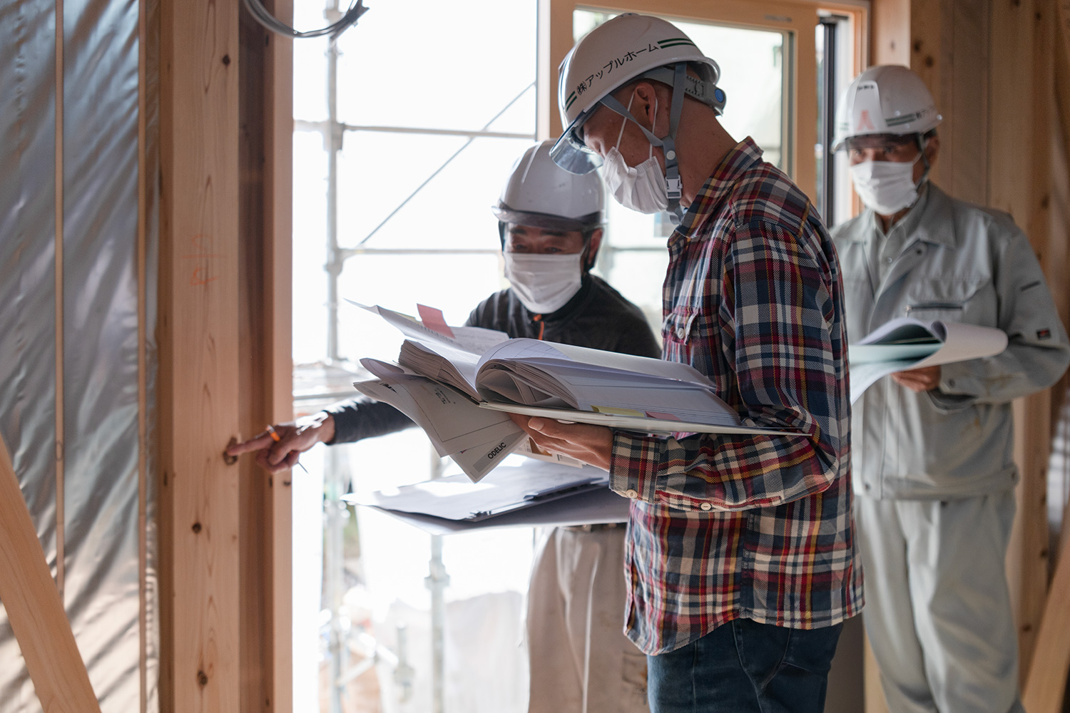 施工図と現場を突き合わせて断熱の納まりを確認する監督と職人(コストは材料費だけでなく納まりと施工手間で決まる)