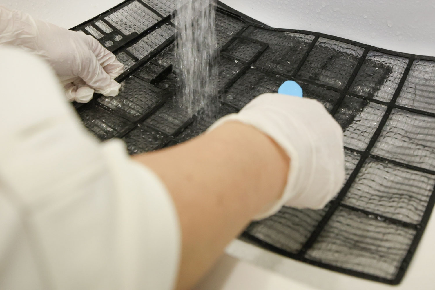 換気システムのフィルターを掃除機で清掃する様子