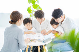 はじめての家づくりで注文住宅のプランを工務店と相談する家族