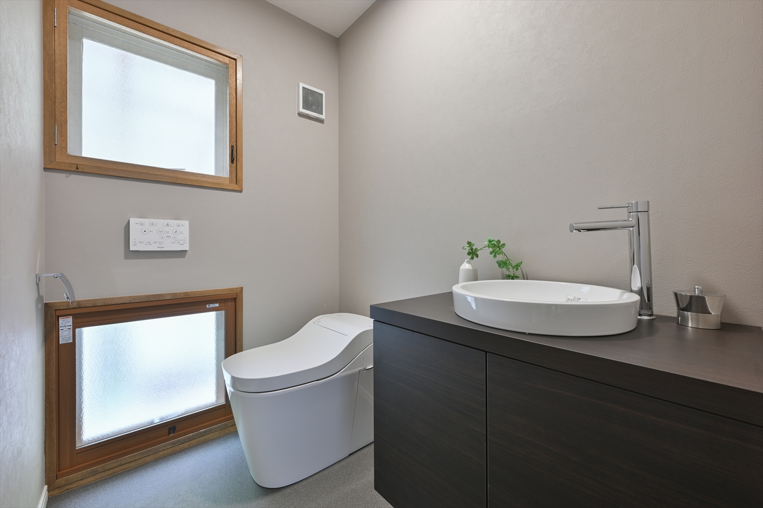 上下に窓を設けた明るいトイレ空間とカウンター一体型手洗い