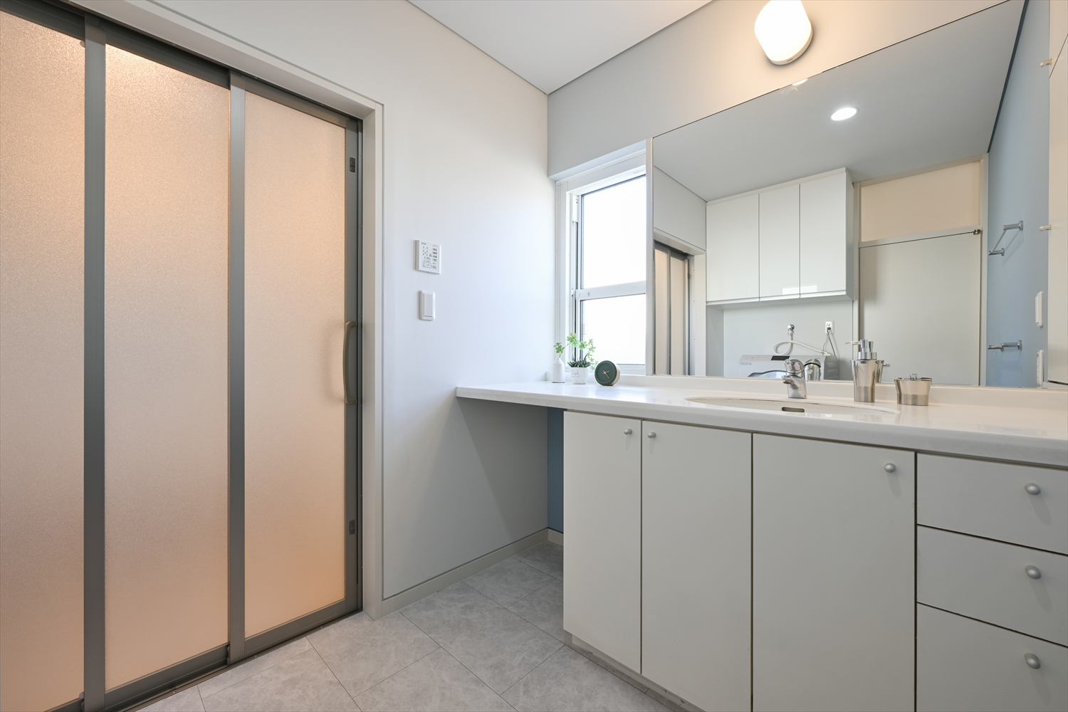 ワイドカウンターと大きな鏡の洗面スペース（リフォーム後）