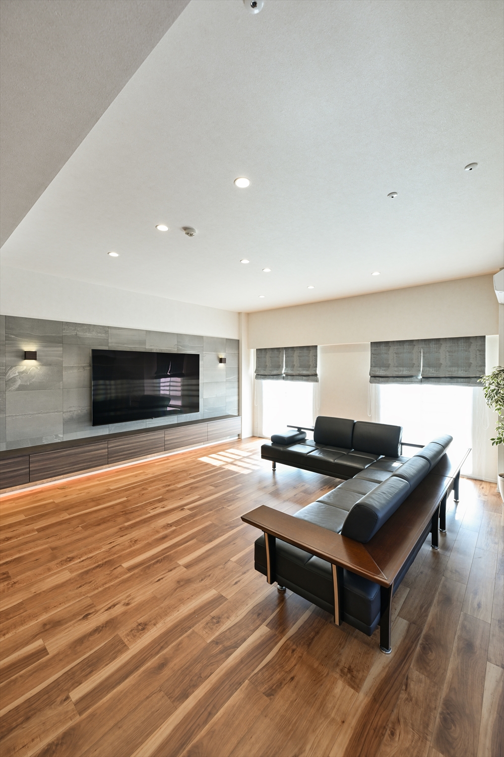 造作TVボードと壁面タイルが映えるリビング（ソファ配置・木目フローリング）