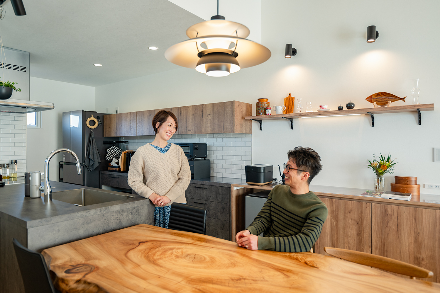川越市のR+house平屋注文住宅のダイニングキッチンで会話を楽しむご夫婦の様子(オーナーズインタビュー)