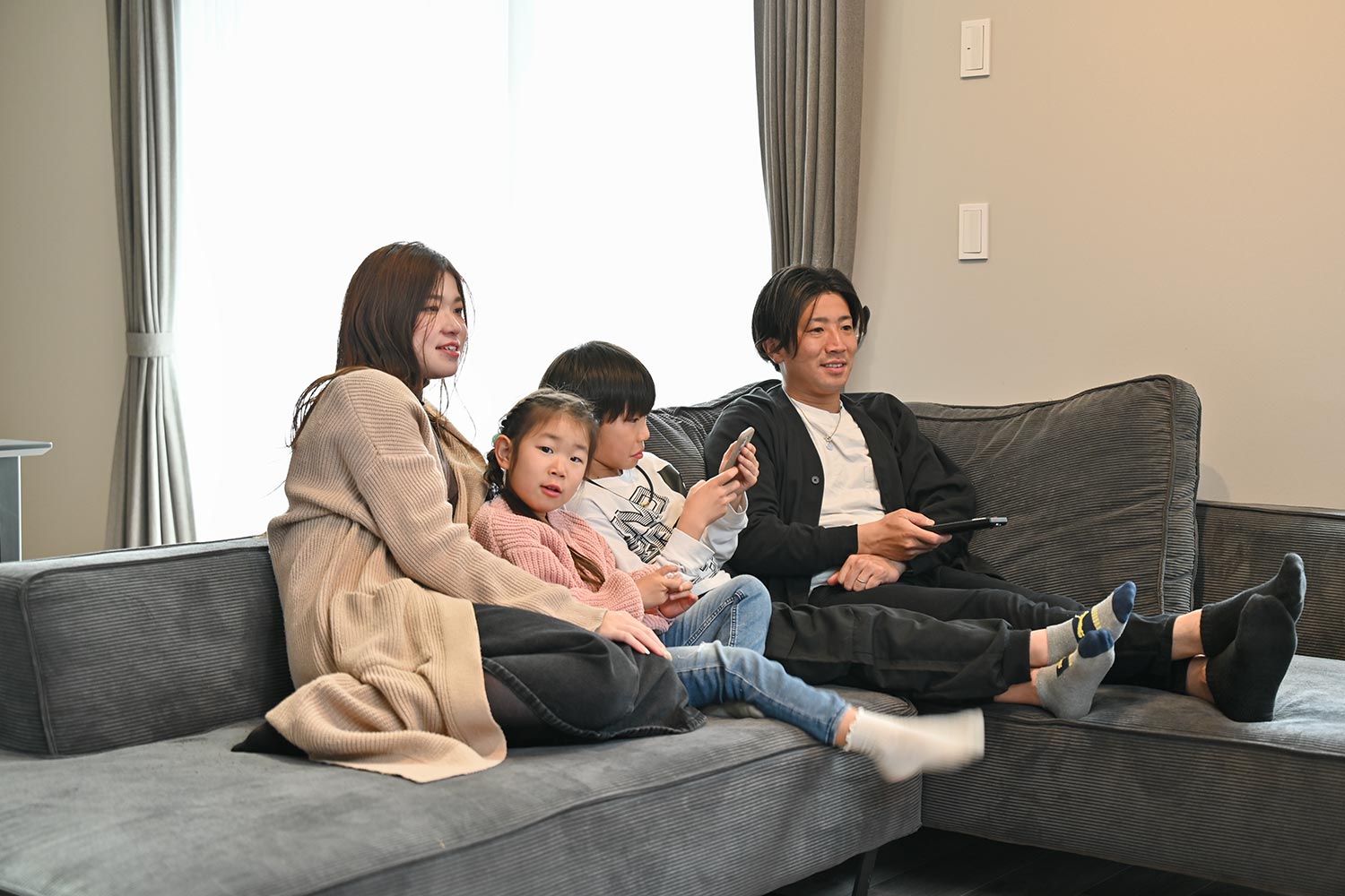全館空調のWELL＋注文住宅のリビングでソファに並んでくつろぐ所沢市H様ご家族