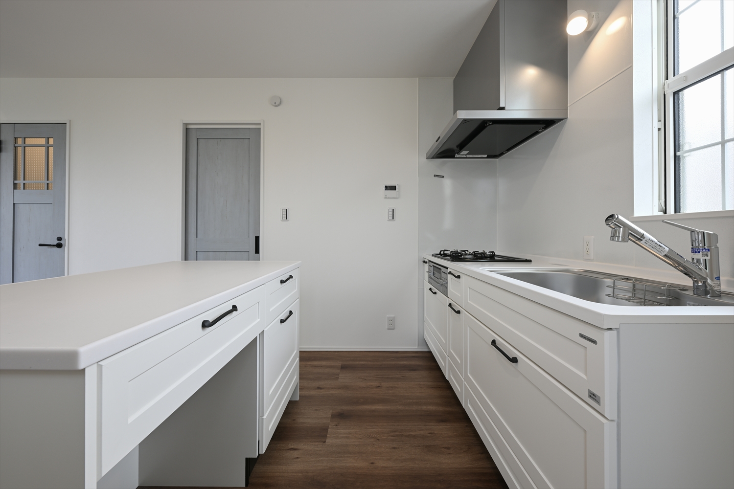 白いキッチンとカウンターが並ぶLDKのキッチン空間