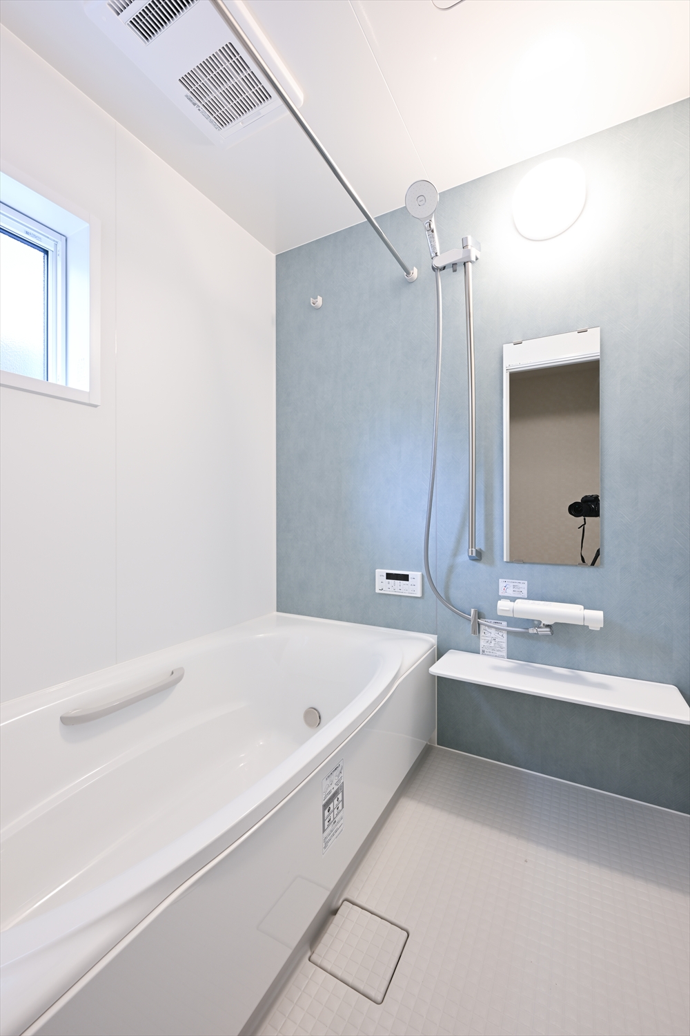 ブルー系アクセントパネルの浴室、浴槽とシャワー、窓があるユニットバス