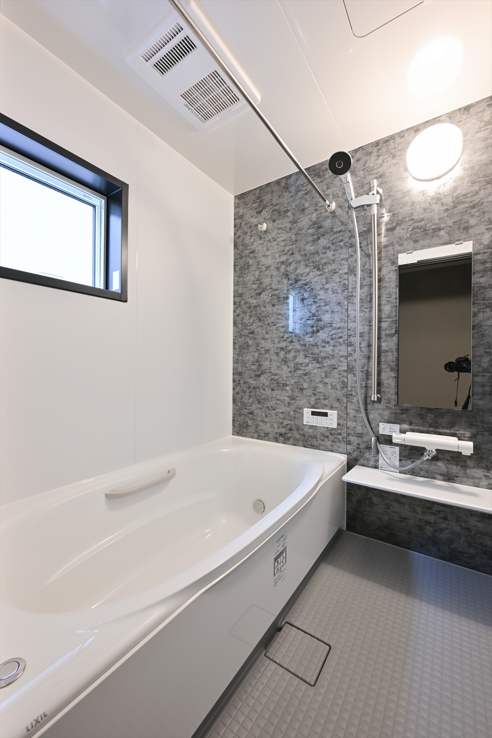 ダーク系アクセントパネルの浴室、浴槽とシャワー、窓があるユニットバス