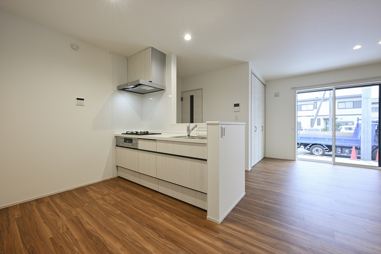 明るい面材の対面キッチン、3口ガスコンロ付きのLDK空間