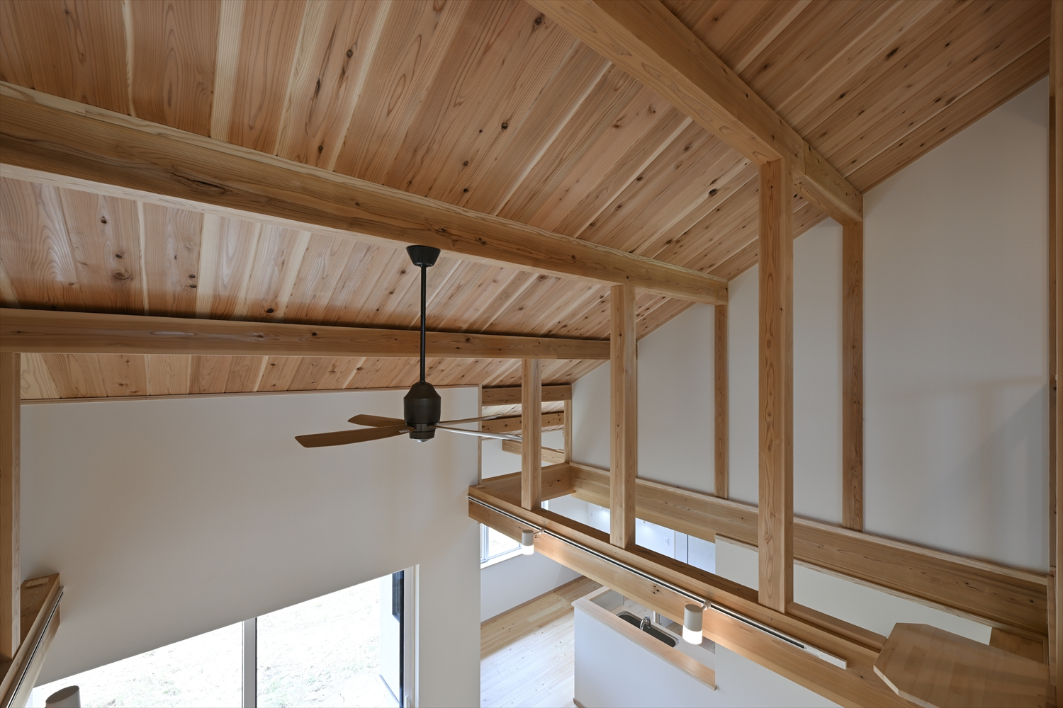 2階廊下から見下ろす吹き抜け、木の梁と勾配天井