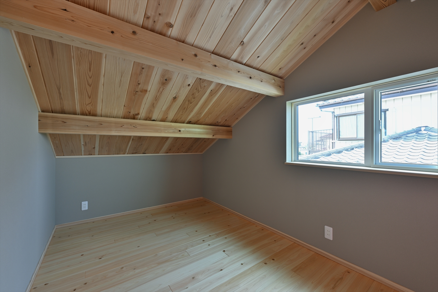 小屋裏空間を利用した主寝室、木板の勾配天井と小窓
