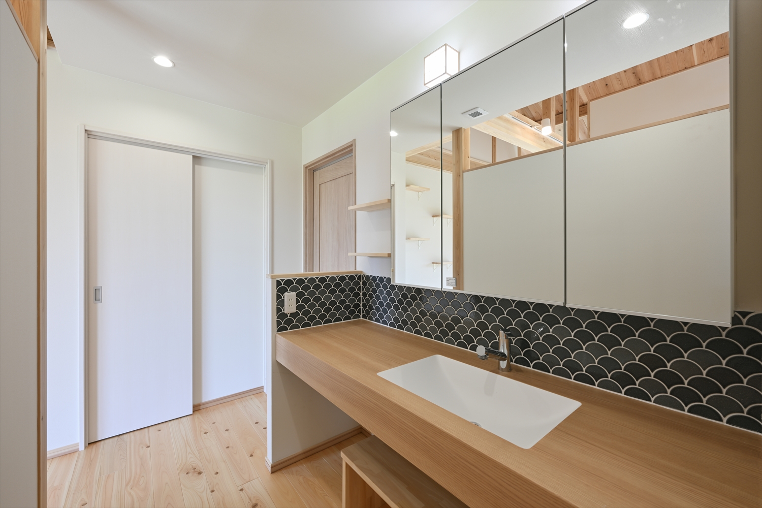 木のカウンターの造作洗面台、ボウル型洗面器と収納扉