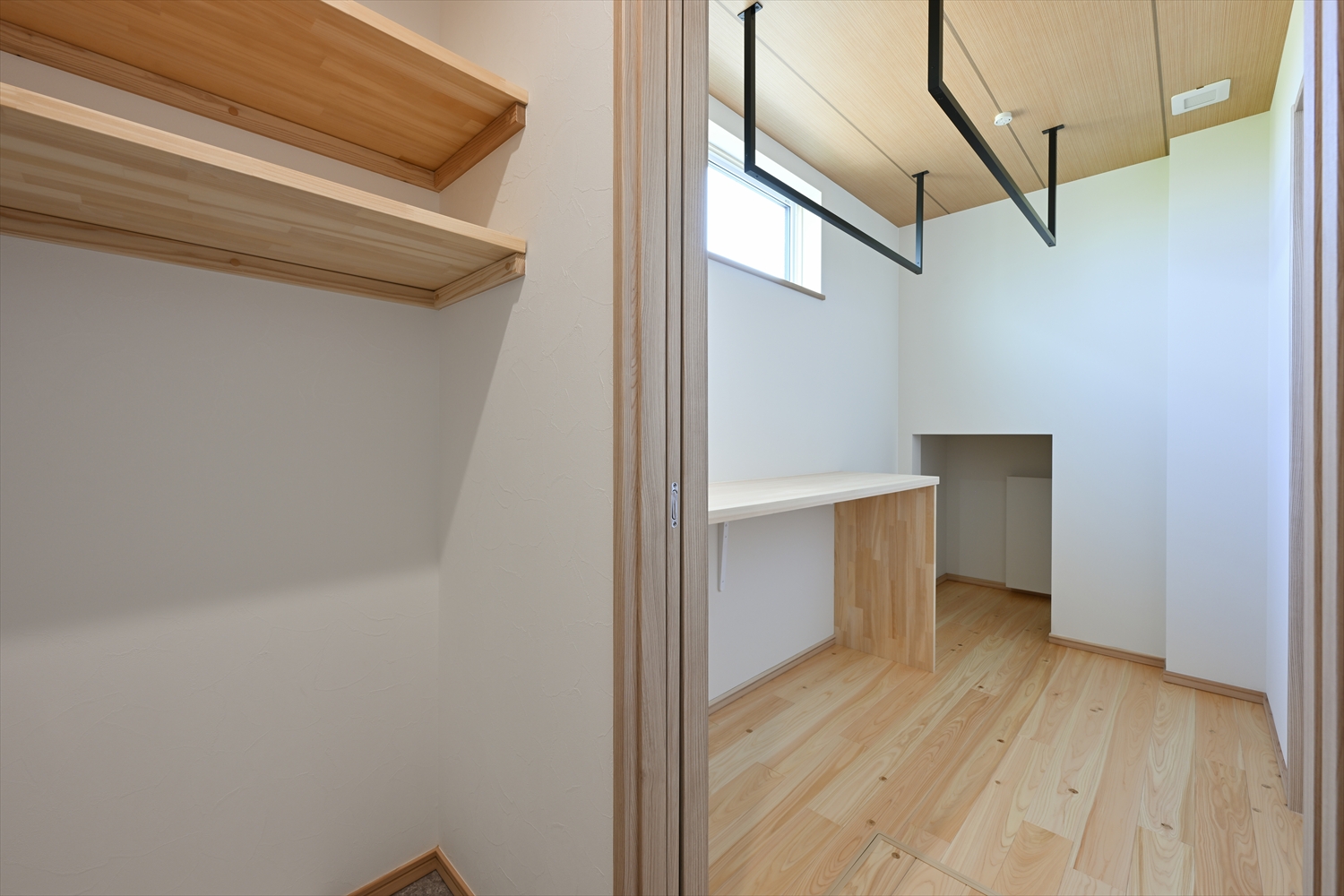 室内物干しバーのあるランドリールーム、作業カウンターと棚