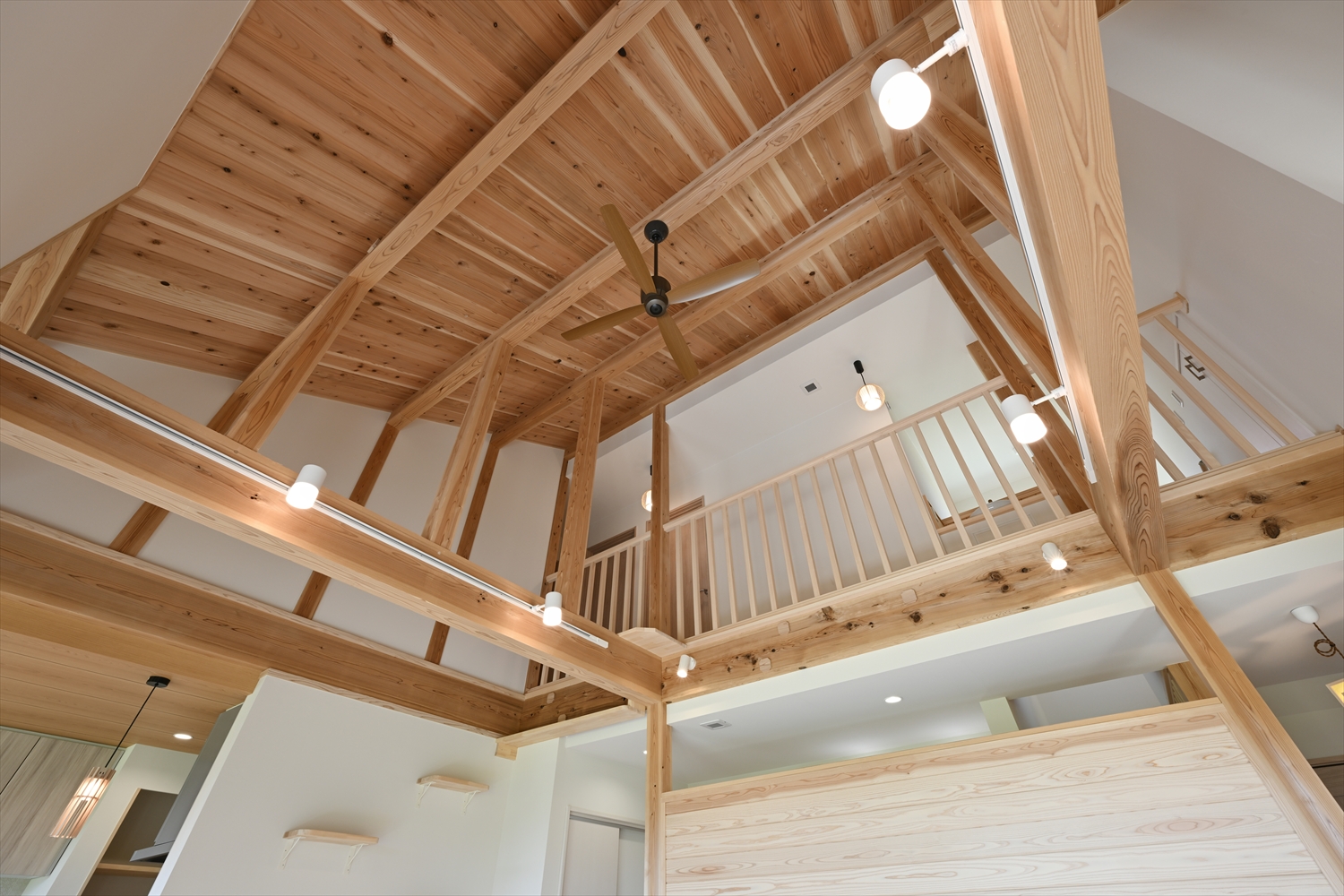 吹き抜けの勾配天井と梁、シーリングファンのあるリビング