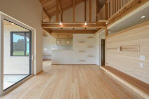 大開口のあるリビング、木のアクセント壁と吹き抜け