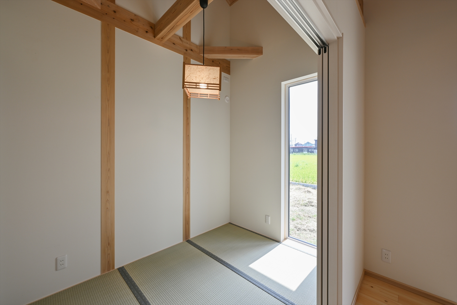 リビング続きの畳コーナー、縦長窓とペンダント照明