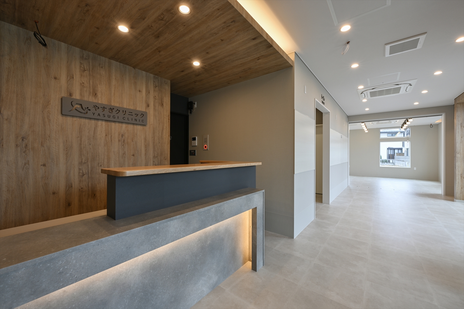 受付カウンターと木目天井のエントランス、サインのある壁面