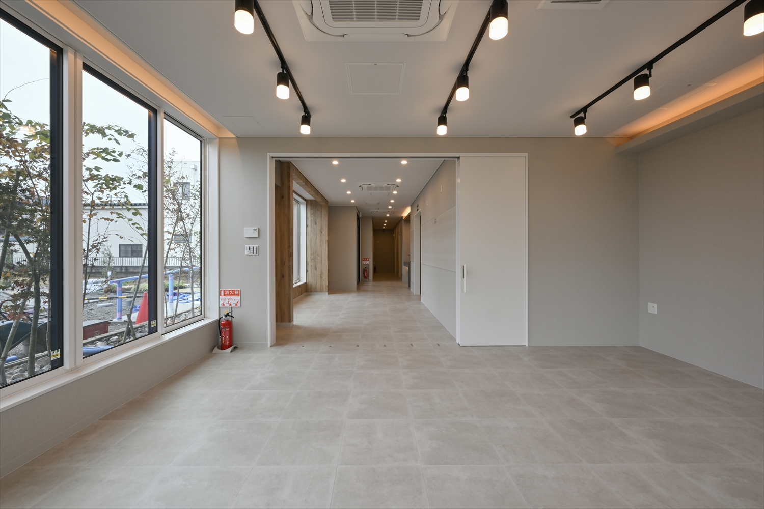 多目的ルームから待合・廊下方向を見た室内、照明計画が分かる眺め