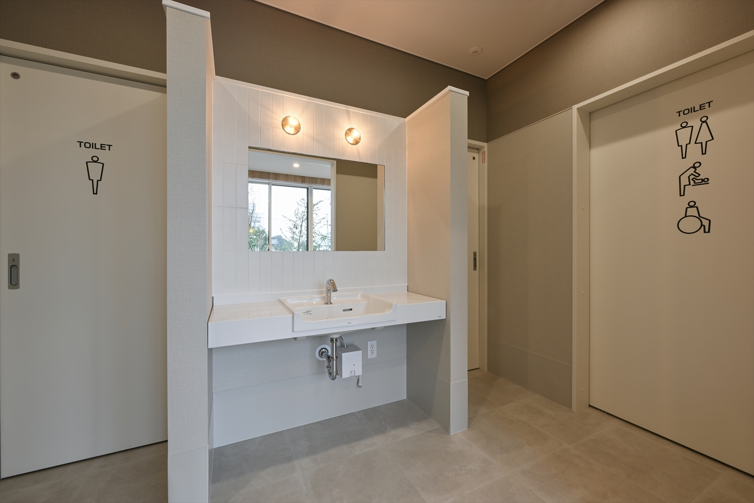 トイレ前の共用洗面スペース、鏡付き洗面台とピクトサイン