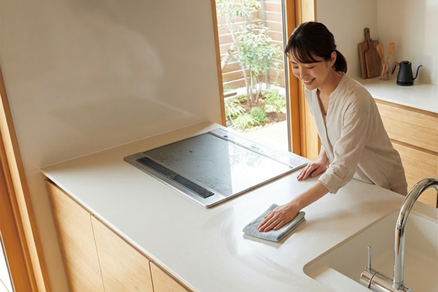 広いワークトップを拭いてお手入れする様子。フラットなカウンターで掃除がしやすいキッチンリフォームのイメージ