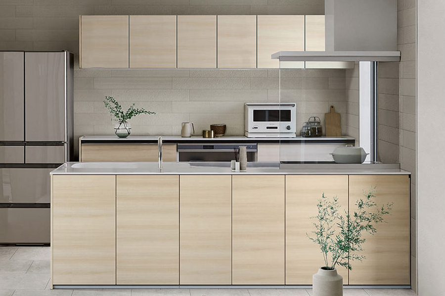 LIXILのシステムキッチン「ノクト」の施工イメージ。明るい木目の扉と対面カウンターで、料理がしやすいキッチンリフォーム