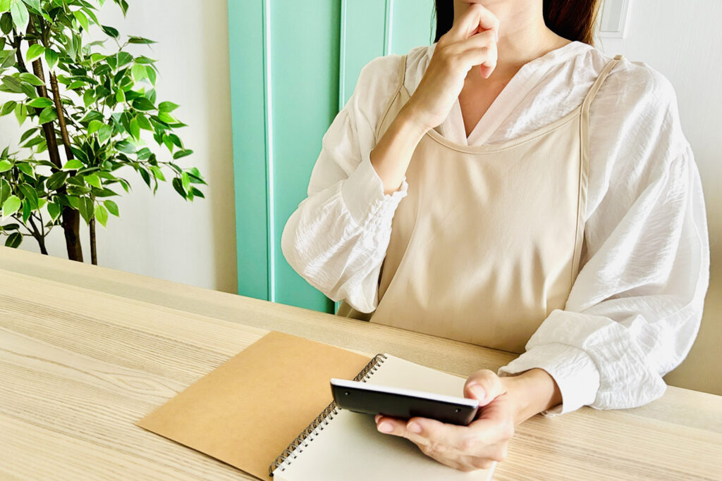 家計簿と電卓で総予算を考える様子