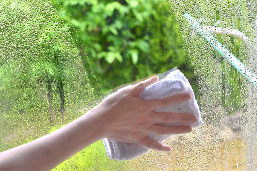 窓ガラスの結露を拭き取っている様子（結露対策の断熱リフォーム）