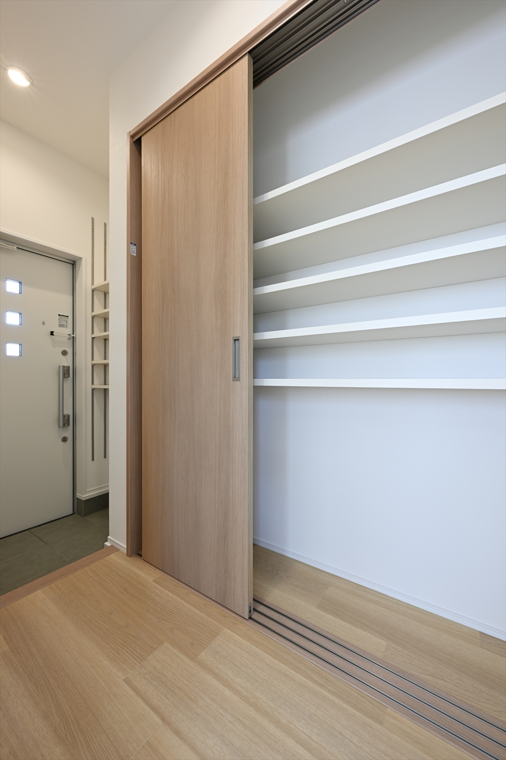 玄関横に大容量の可動棚収納を備えたアパート室内