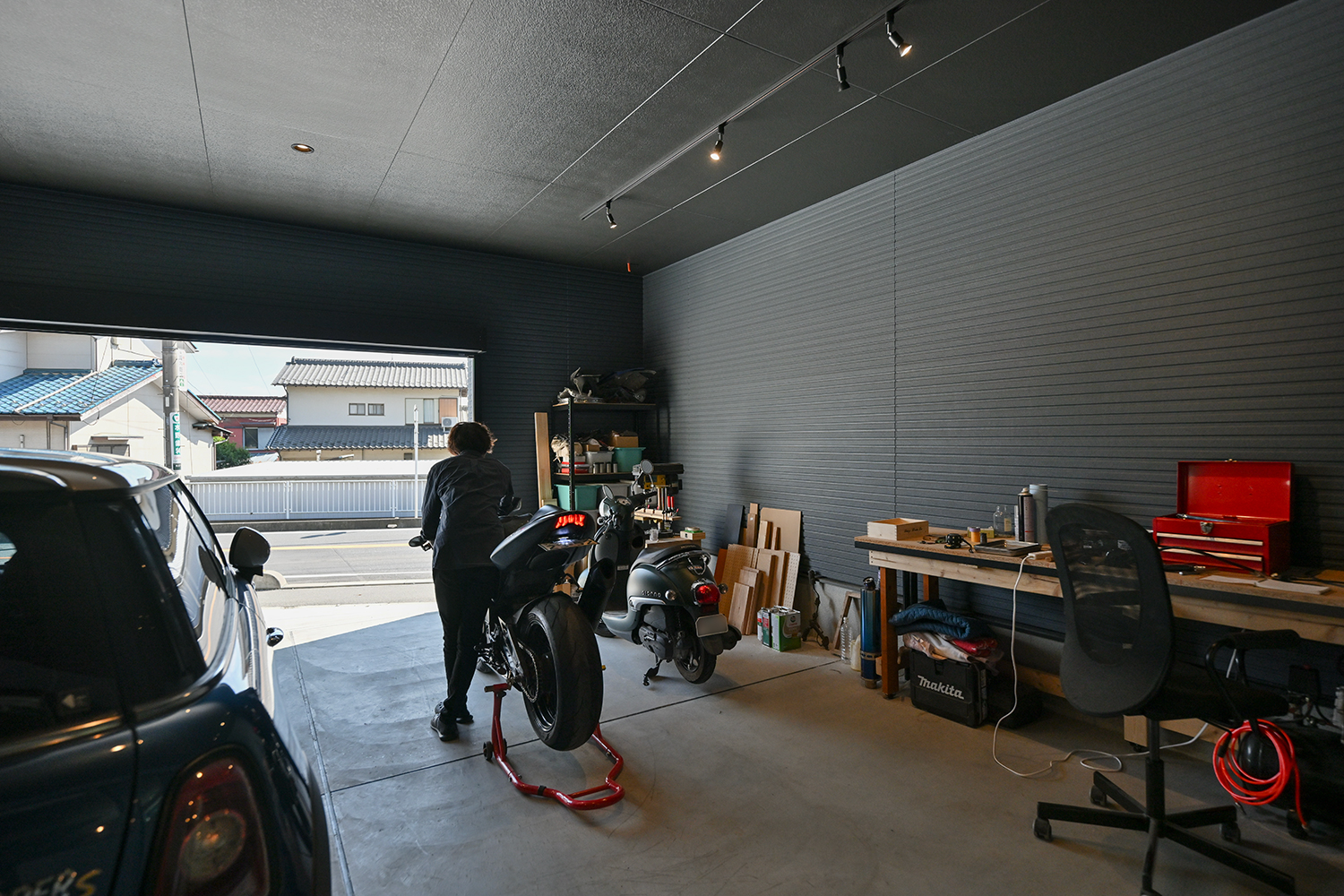 車とバイクを置き、工具棚や作業台を備えた平屋ガレージハウスのガレージ